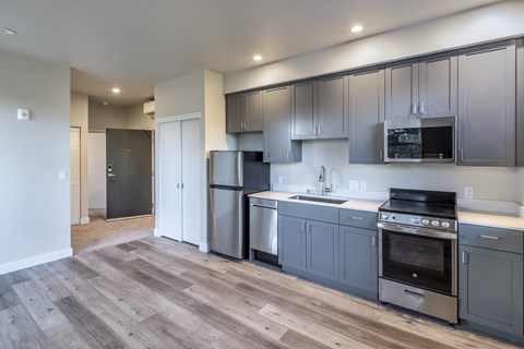 A modern kitchen with stainless steel appliances and wooden flooring.at 888 Fourth Street Apartments, LLC, Santa Rosa