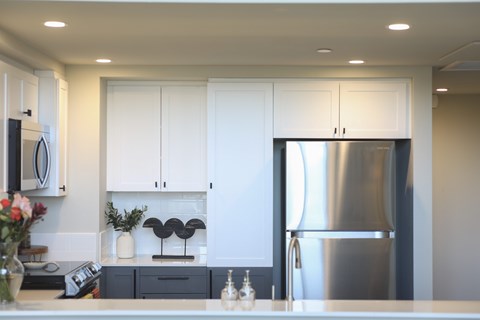 A modern kitchen with white cabinets and a stainless steel refrigerator.at 888 Fourth Street Apartments, LLC, California, 95404