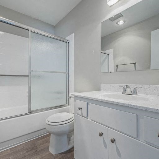 a white bathroom with a toilet and a sink at The Arches Apartments, El Cajon