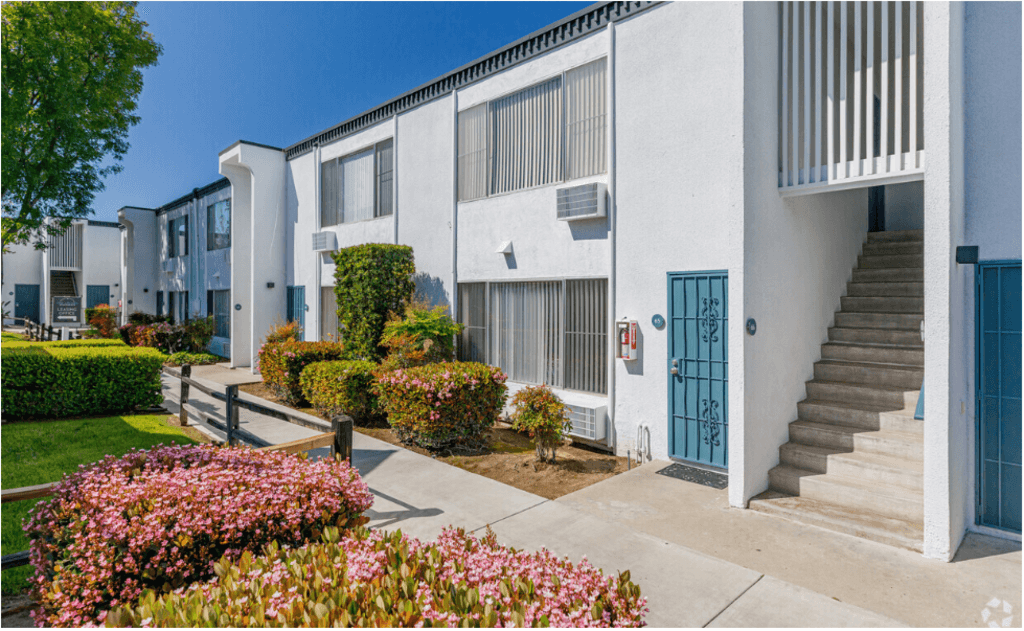 a white apartment building with a staircase and a blue doorat The Arches Apartments, LLC, California