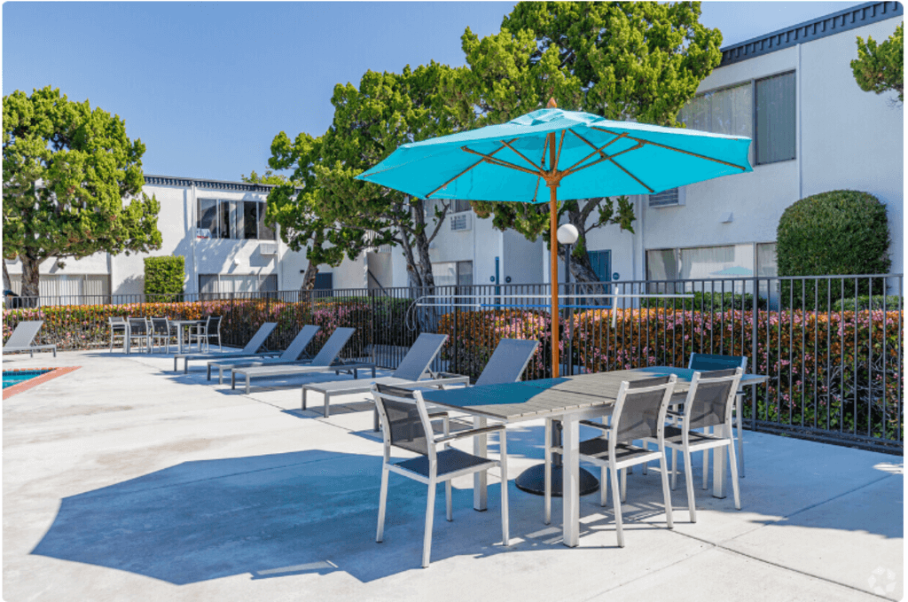 a patio with tables and chairs and an umbrellaat The Arches Apartments, LLC, El Cajon, 92021