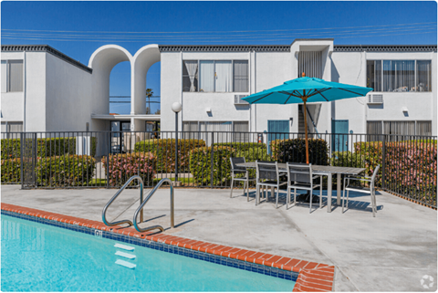 our apartments have a swimming pool and a patio with a table and umbrellaat The Arches Apartments, LLC, El Cajon California