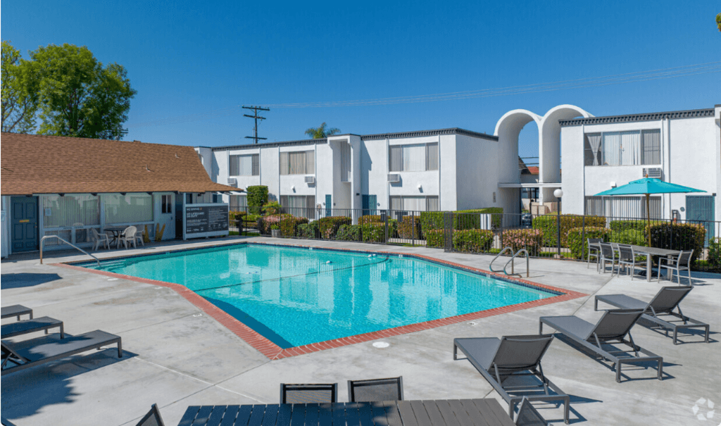 a swimming pool with chairs around it in front of a buildingat The Arches Apartments, LLC, El Cajon