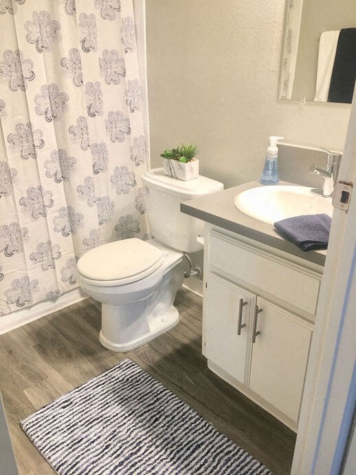 a bathroom with a toilet and a sink and a shower curtain a bathroom with a toilet and a sink and a shower curtain at The Marq Apartments LLC, Los Angeles