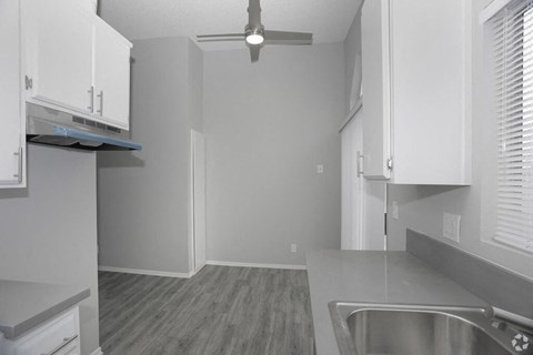 a kitchen with white cabinets and a ceiling fan