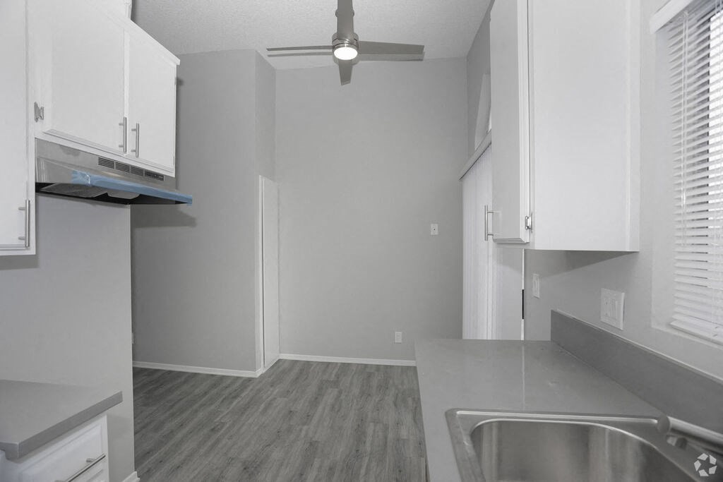 a kitchen with white cabinets and a ceiling fan a kitchen with white cabinets and a ceiling fan at The Marq Apartments LLC, Los Angeles, California