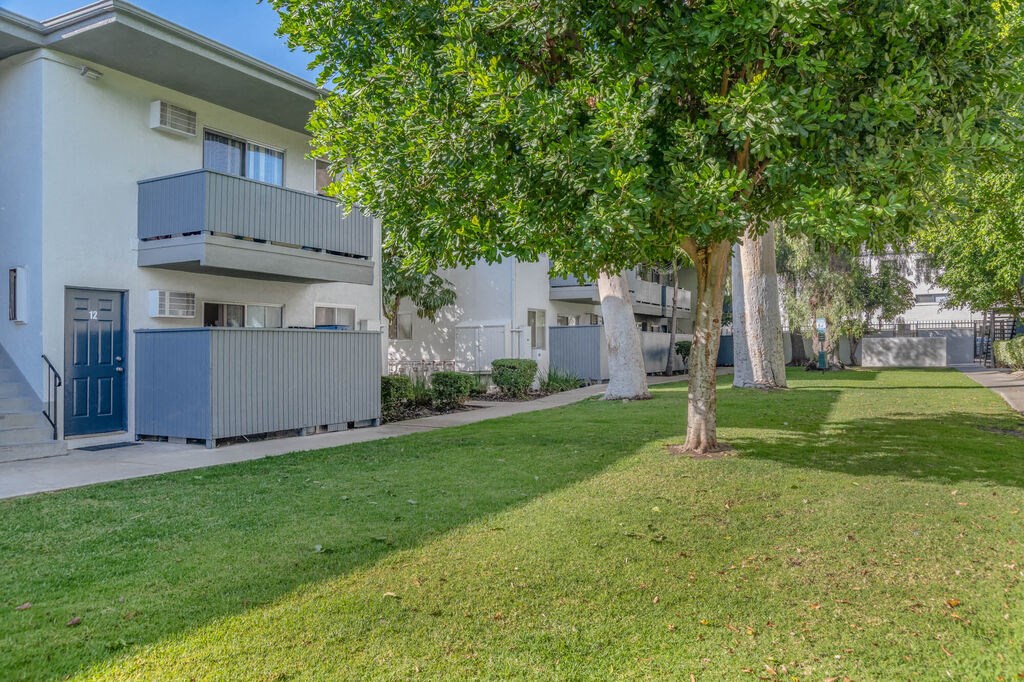 an apartment building with a lawn and trees in front of it at BLVD Apartments LLC, Tarzana, CA