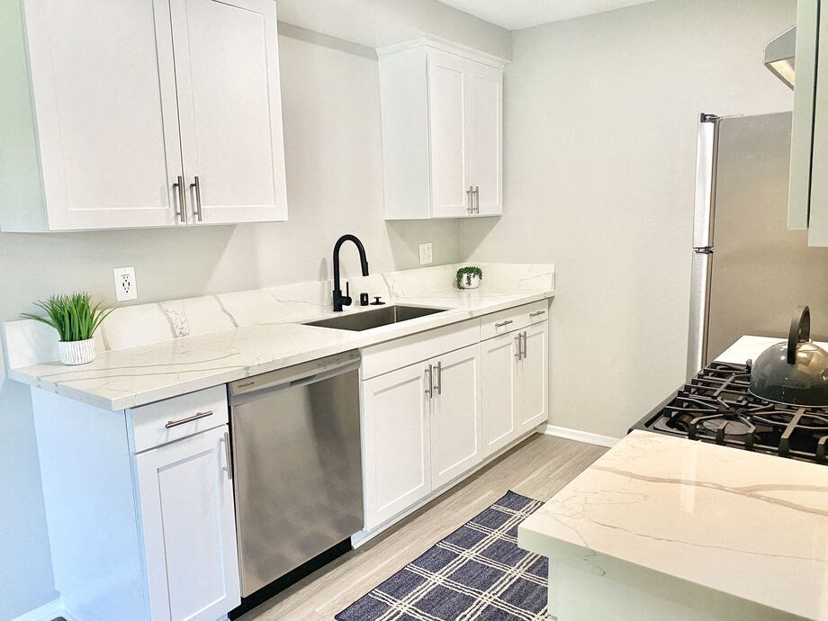 a kitchen with white cabinets and a stainless steel refrigerator at BLVD Apartments LLC, Tarzana, CA