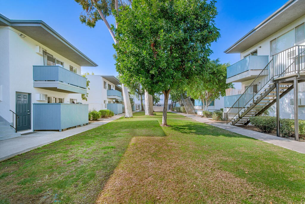a grassy area between two buildings with trees in the middle at BLVD Apartments LLC, Tarzana, 91356