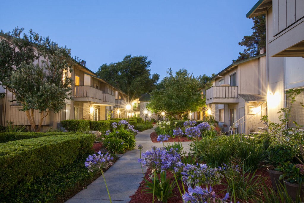 a sidewalk in front of some apartments with flowers at Campbell West, Campbell California