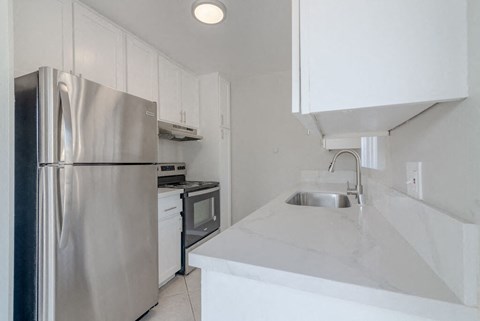a kitchen with white counter tops and a stainless steel refrigerator