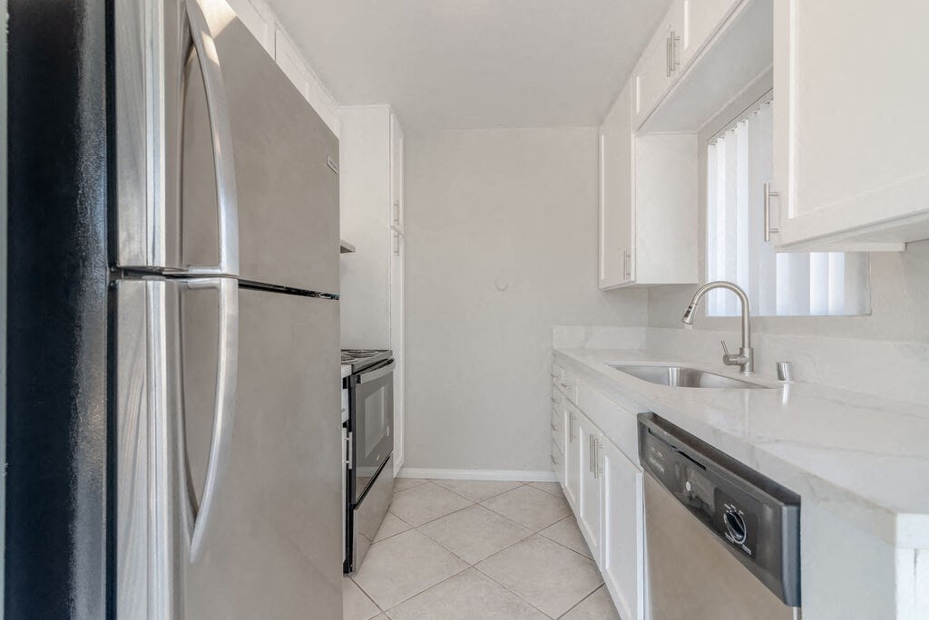 a kitchen with white cabinets and a stainless steel refrigerator at Citra Apartments LLC, California