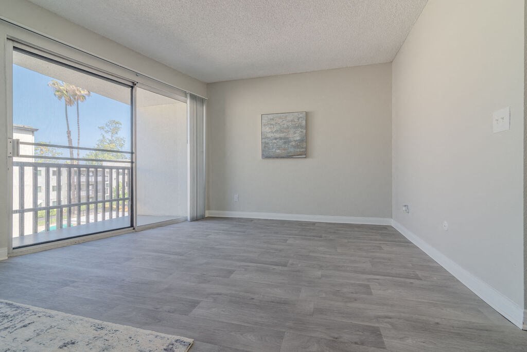 an empty living room with a sliding glass door to a balcony at Citra Apartments LLC, California, 92107