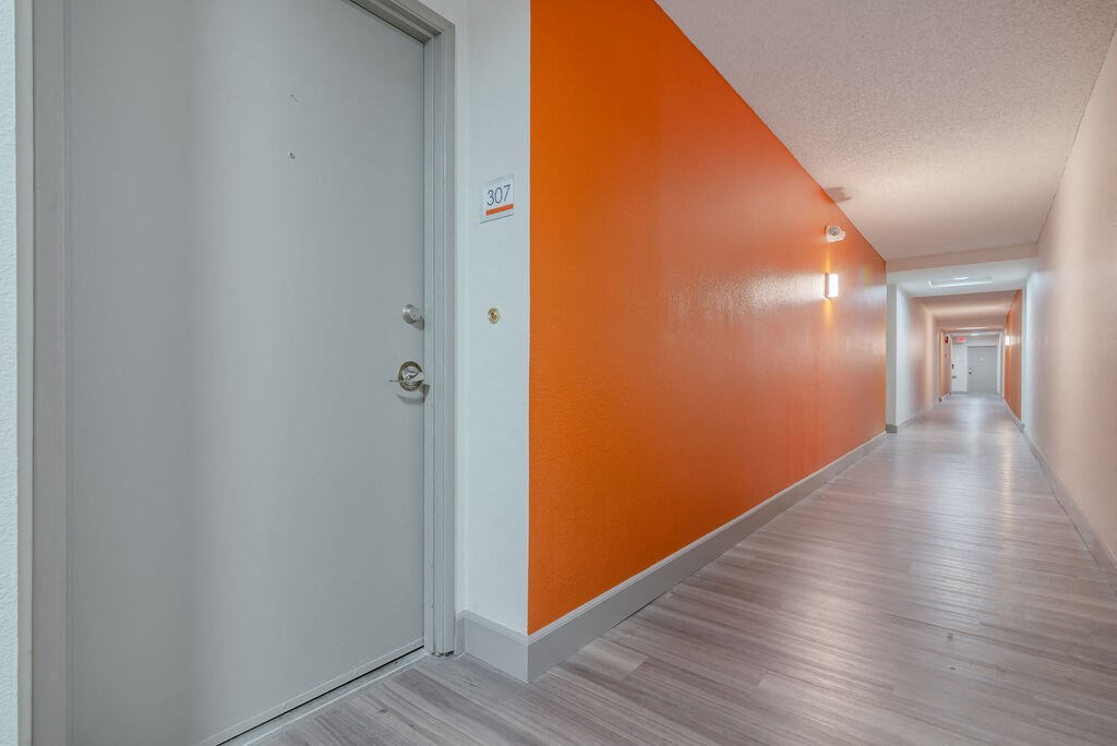 a hallway with an orange wall and a white door at Citra Apartments LLC, California, 92107