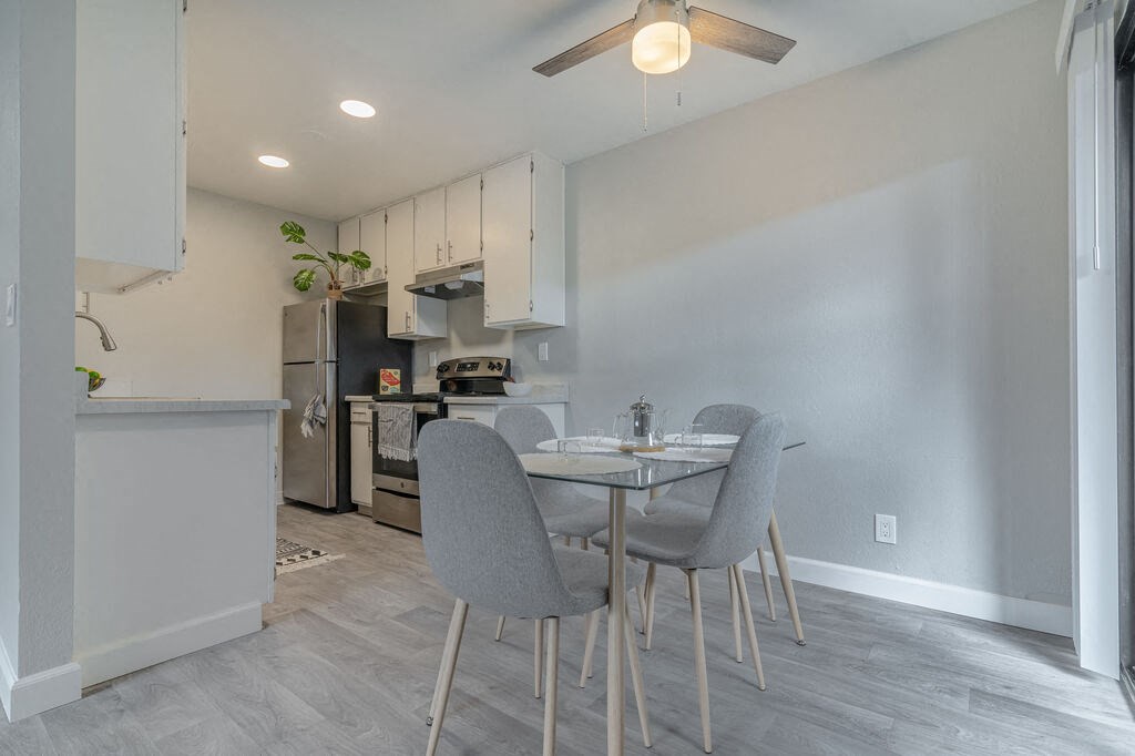 a dining room with a table and chairs and a kitchen at The Gates at The Marina Apartments, California