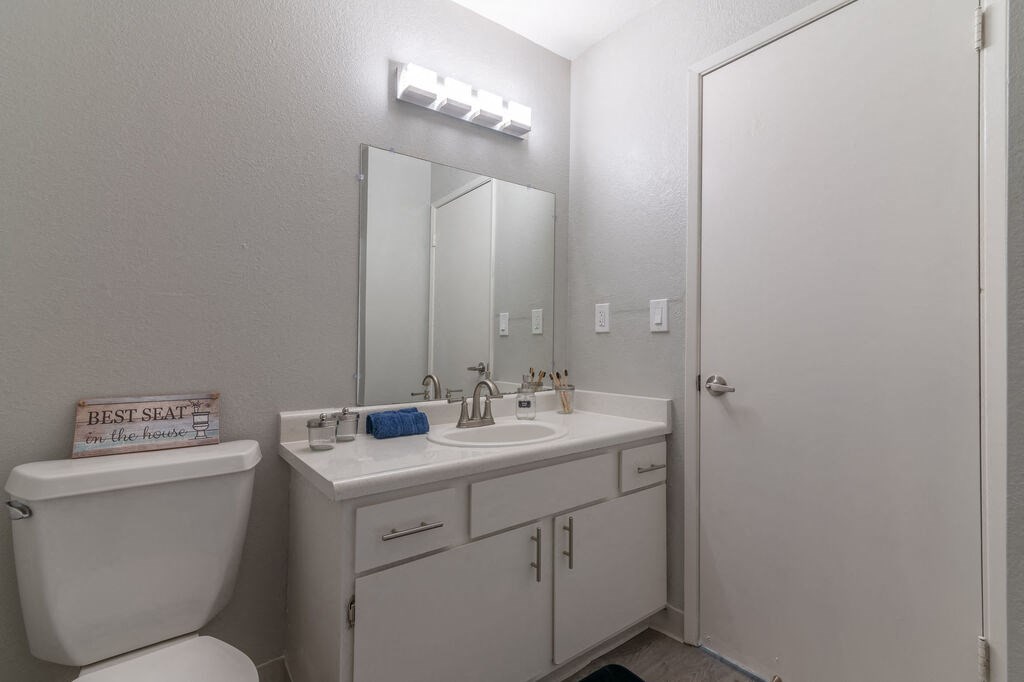 a bathroom with a toilet sink and a mirror at The Gates at The Marina Apartments, Marina, CA 93933