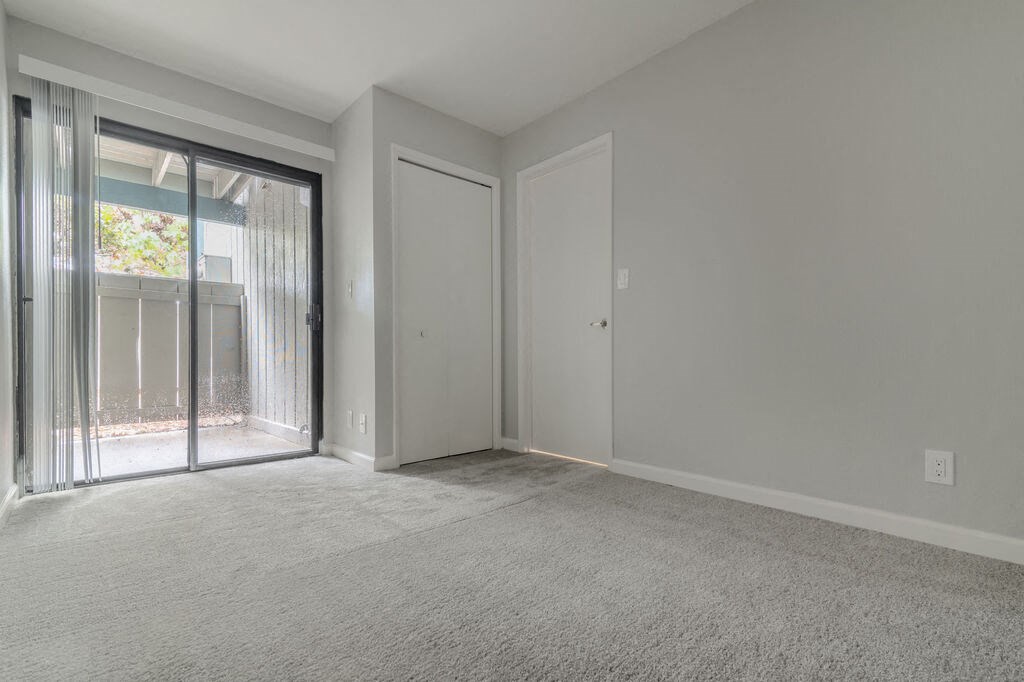an empty living room with a sliding glass door to a patio at The Gates at The Marina Apartments, California, 93933