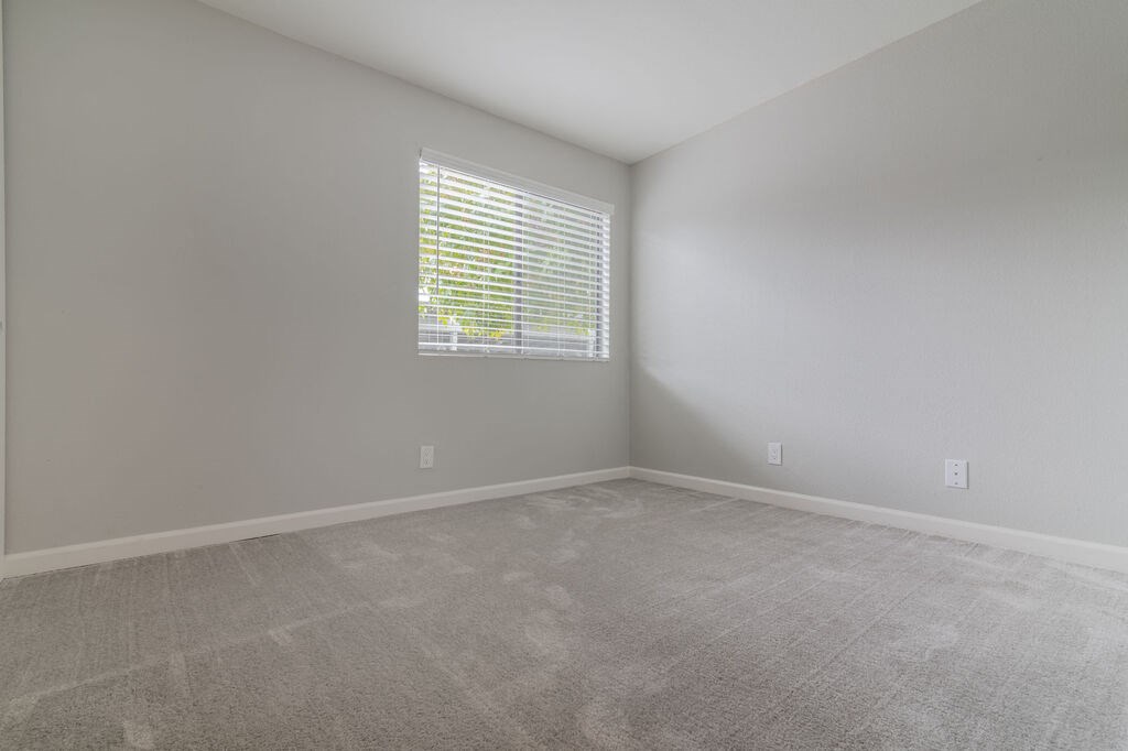 an empty room with a window and carpet at The Gates at The Marina Apartments, Marina, CA