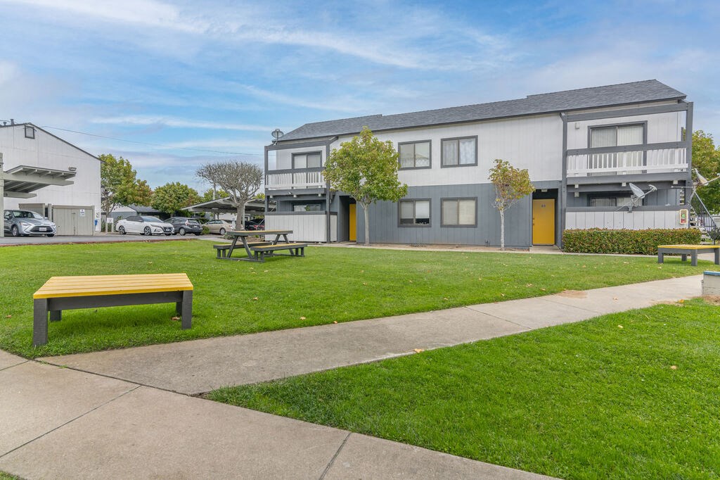 a park with a bench in front of a building at The Gates at The Marina Apartments, Marina, CA