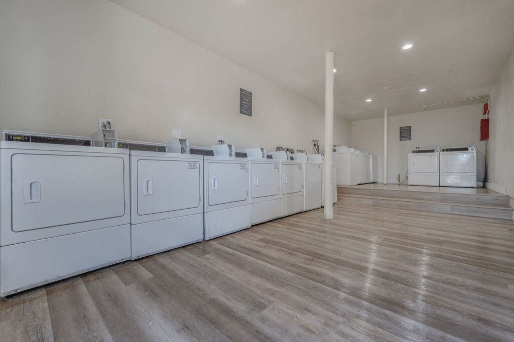 a row of white washers and dryers in a room with wood floors at The Hills Apartments at Thousand Oaks, California
