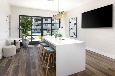 a kitchen with a long white counter top and a bar with stools
