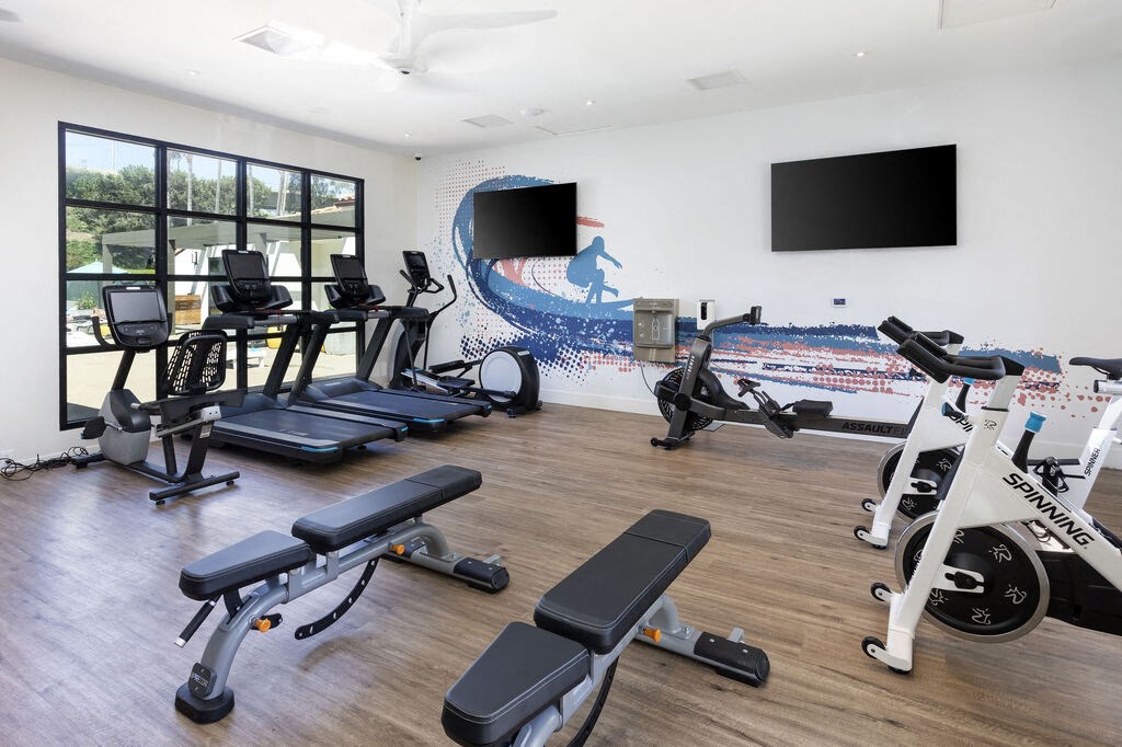 a gym with cardio equipment and a wall mural of the beach at La Jolla Blue, San Diego