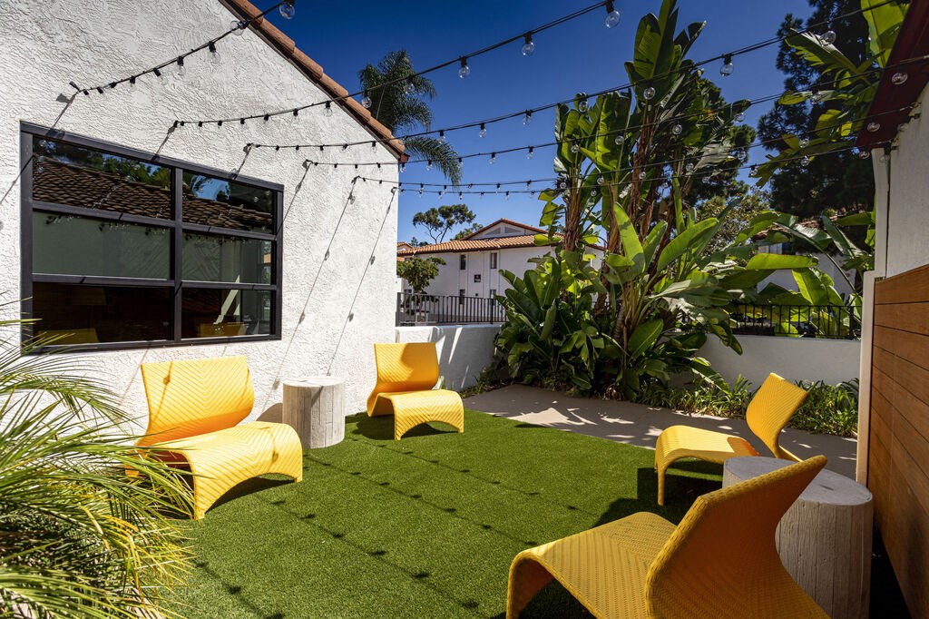 a backyard with yellow chairs and a green lawn at La Jolla Blue, San Diego, CA 92122