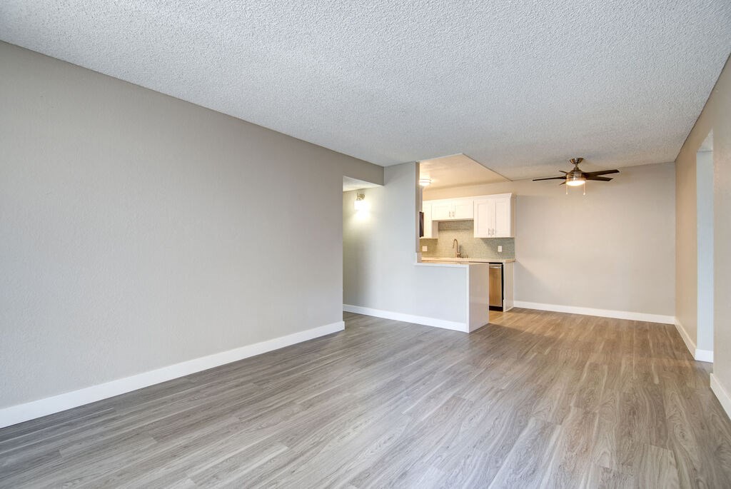 an empty living room and kitchen with wood flooring and a ceiling fan at La Jolla Blue, San Diego, CA