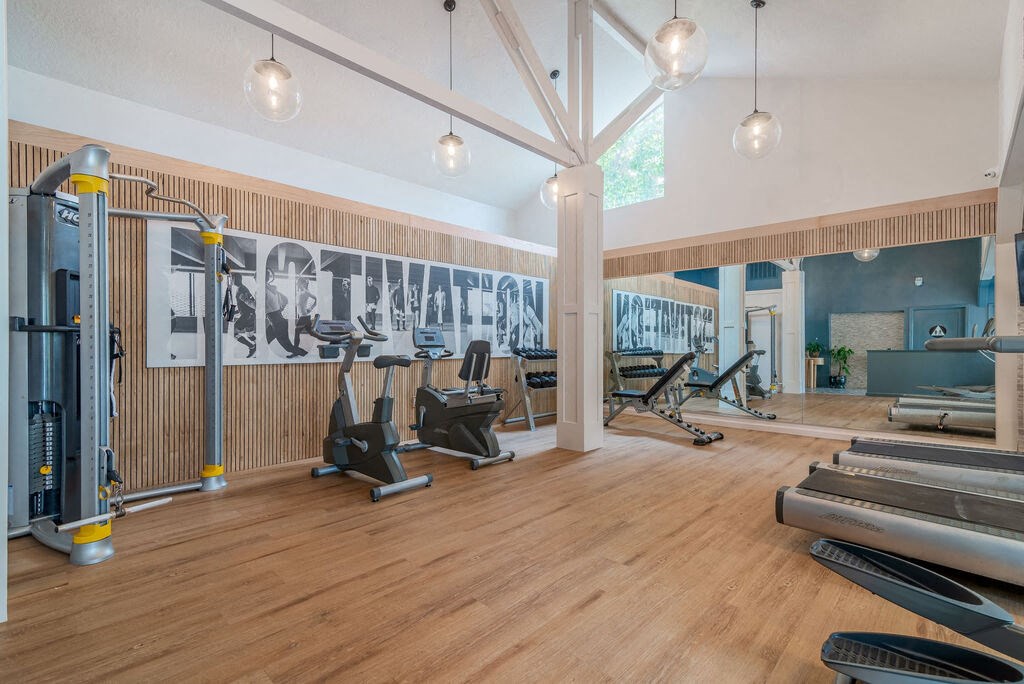 a gym with cardio machines and weights on a wooden floor at Napa Green Apartments LLC, Napa, CA 94559