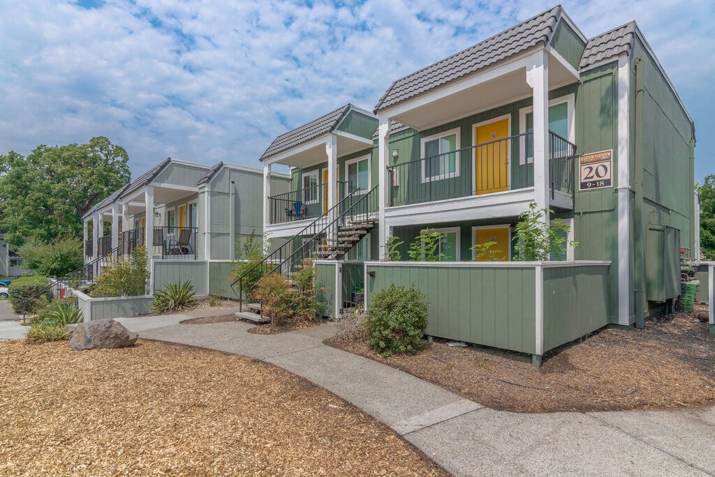 a row of green houses with yellow doors and a sidewalk at Napa Green Apartments LLC, California