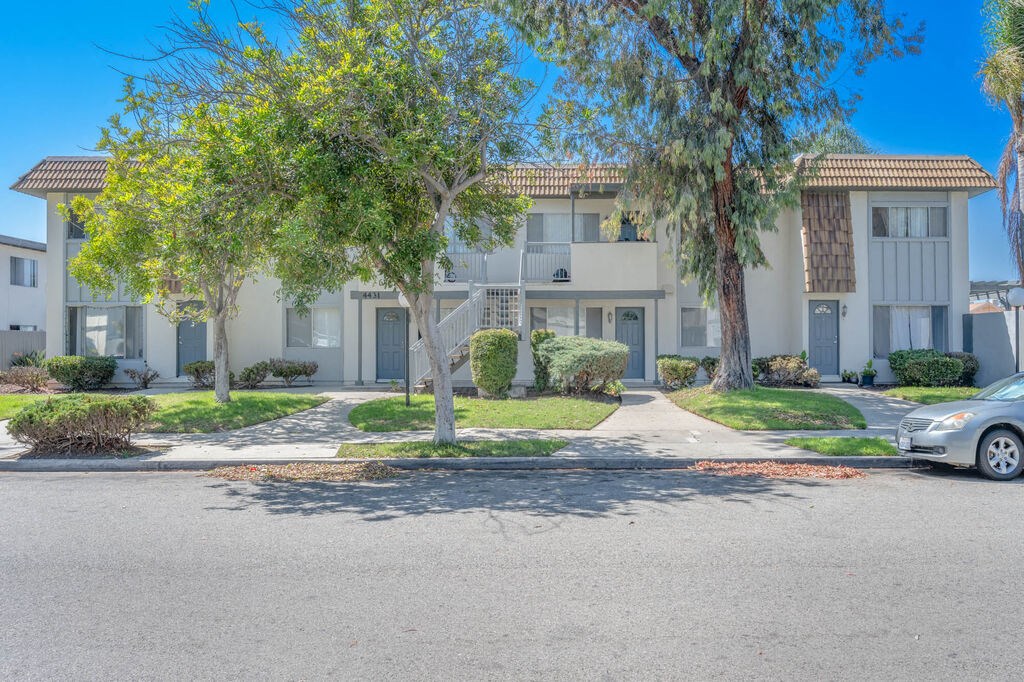 an apartment building with a street and trees in front of it at Ocean Villas, Oxnard, CA