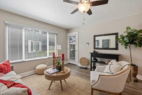 A living room with a fan, a chair, and a table with a vase on it.