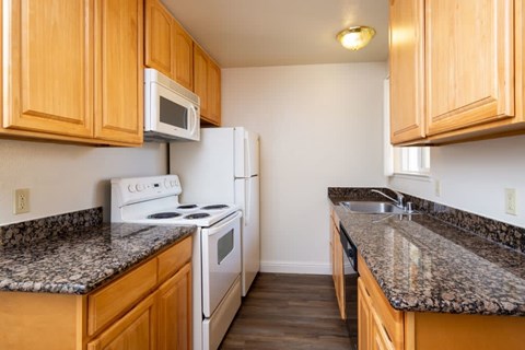 A kitchen with wooden cabinets and granite countertops.