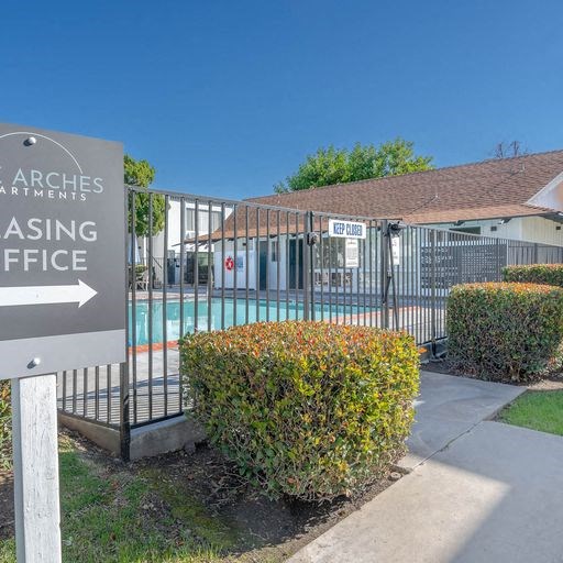 a building with a sign in front of a pool at The Arches Apartments, El Cajon