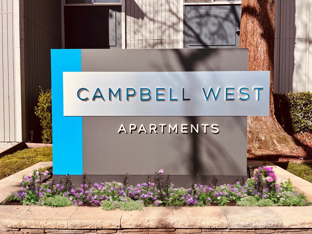 a sign that says apartments in front of flowers at Campbell West Apartments, California
