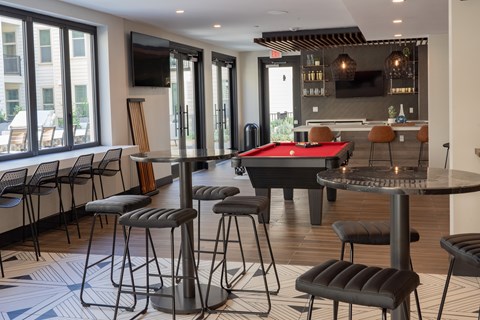 A room with a pool table and bar stools.