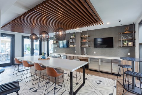 A modern kitchen with a long white table and chairs.