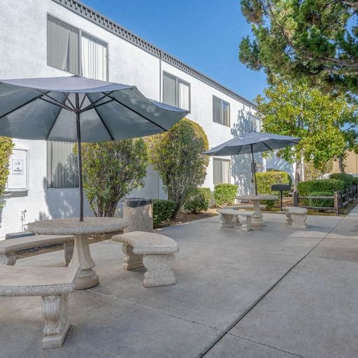 a patio with benches and umbrellas in front of a building