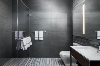 A bathroom with a toilet, sink, and shower at SKY Apartments, New York, NY, 10036