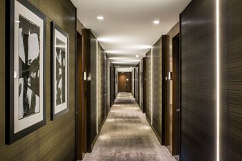 A long hallway with a series of doors on the right and framed pictures on the left. at SKY Apartments, New York, NY