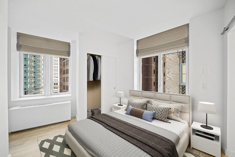 Bright bedroom with dual windows and city views at ARIA 90-100 John Apartments, New York, NY