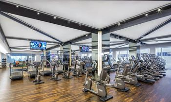 a gym with cardio machines and weights on a wooden floor at SKY Apartments, New York