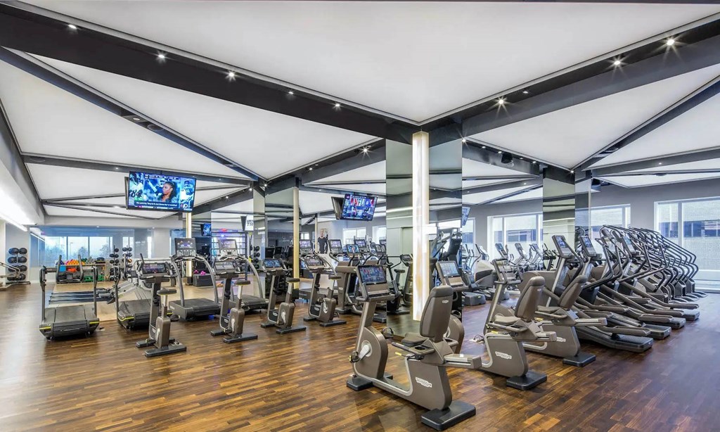 a gym with cardio machines and weights on a wooden floor at SKY Apartments, New York
