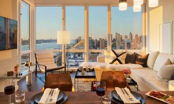 a view of the city from a living room with a couch and a table at SKY Apartments, New York