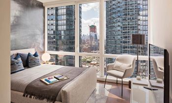 a bedroom with a bed and a view of the city at SKY Apartments, New York, NY