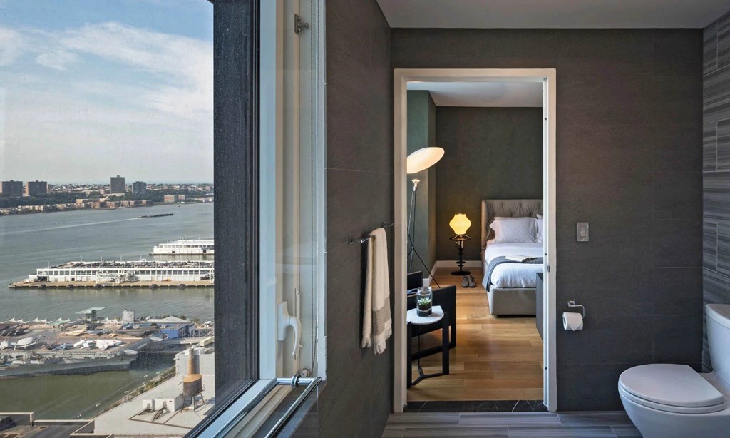 a hotel room with a view of the water and a bed at SKY Apartments, New York, 10036