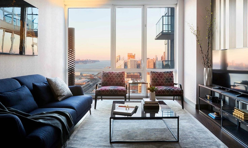 a living room with a view of the city and a couch and coffee table at SKY Apartments, New York 10036