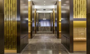a row of elevators in a hotel lobby with gold doors at SKY Apartments, New York, 10036