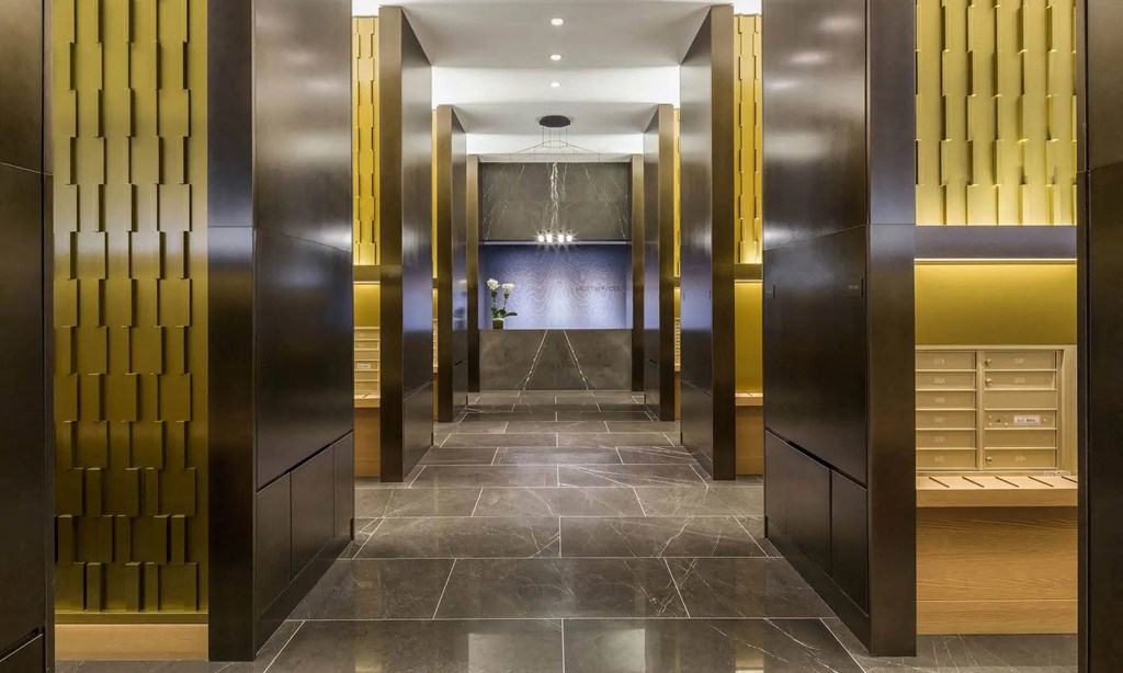 a row of elevators in a hotel lobby with gold doors at SKY Apartments, New York 10036