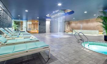 a spa with a jacuzzi and a pool in a room with chairs at SKY Apartments, New York 10036